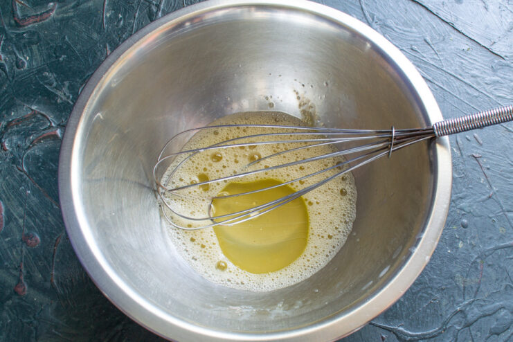 Adding Olive Oil for a Soft and Pliable Dough Olive oil being poured from a bottle into a glass bowl with egg.