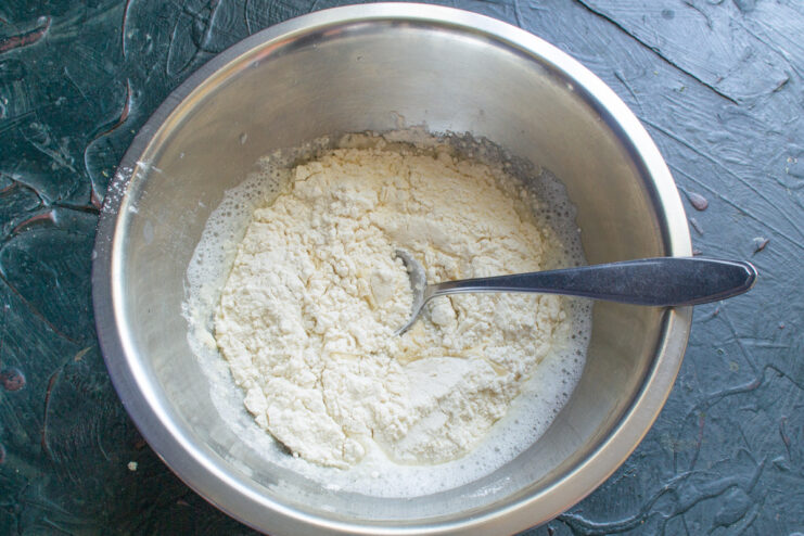 Combining Dry and Wet Ingredients for the Vareniki Dough All-purpose and whole wheat flour being added to the wet ingredients in a bowl.