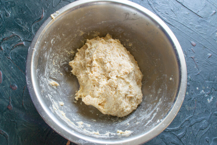 Kneading the Dough to the Perfect Consistency Hands kneading a smooth ball of vareniki dough on a floured surface.
