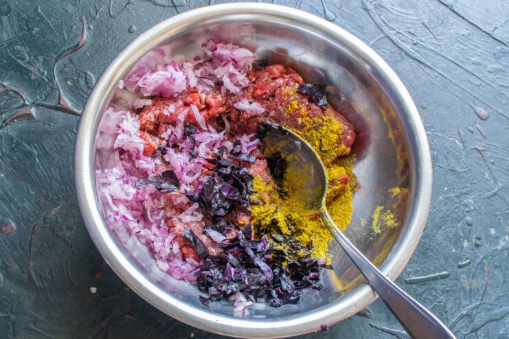 Combining Ingredients for the Savory Meat Filling A bowl of ground beef filling being mixed with grated onion and herbs.