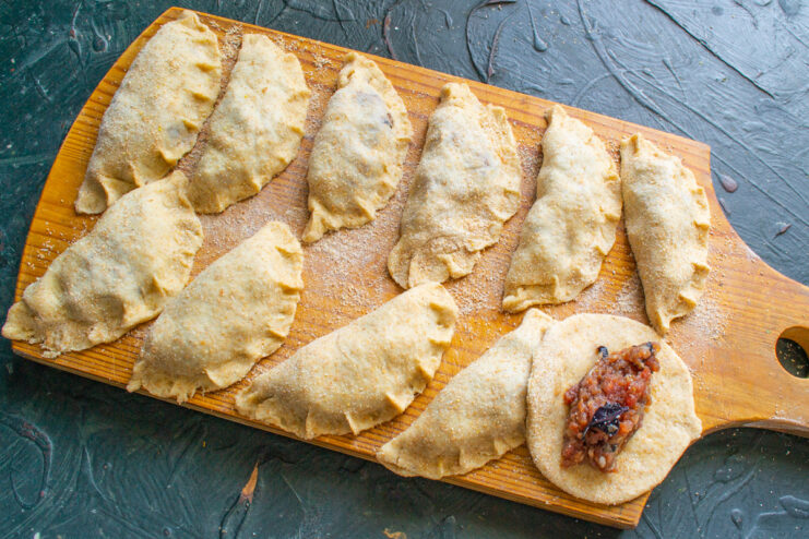 Filling the Vareniki with the Savory Meat Mixture A spoonful of meat filling being placed onto a round piece of rolled-out dough.