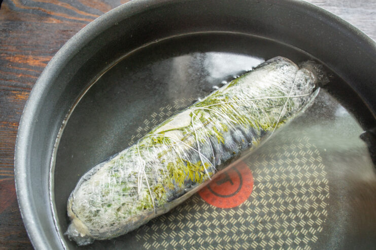 Step 8: Boiling the Mackerel Roll for 10 Minutes The wrapped mackerel roll simmering in a pot of water.