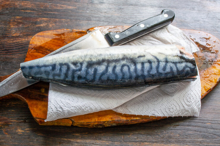 Step 1: How to Properly Clean and Prepare Mackerel for the Roll A whole mackerel being prepared on a cutting board: head and tail removed.