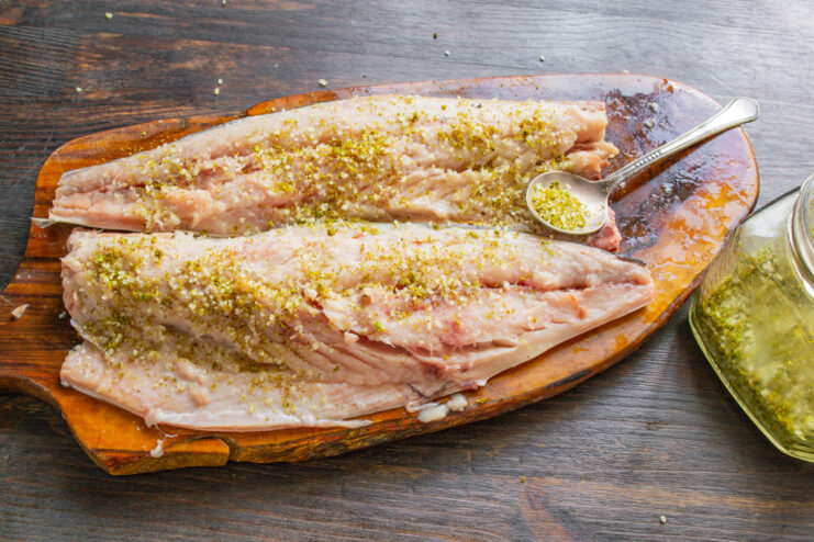 Step 3: Seasoning the Mackerel Fillets with Salt and Spices Mackerel fillets being seasoned with coarse sea salt and garlic powder.