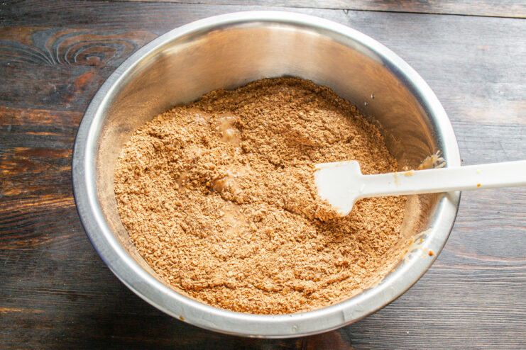 A blender filled with roasted peanuts and rolled oats, being ground into a fine crumb for the cake batter.