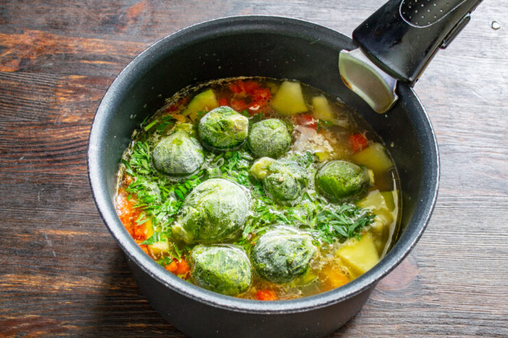 Adding Brussels sprouts to the soup Fresh Brussels sprouts being added to the pot of vegetable soup.