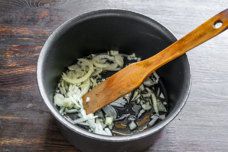 Sautéing onions and garlic to build the soup's flavor base Diced onion and minced garlic being sautéed in a pot with olive oil.