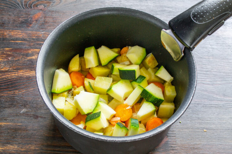 Adding diced zucchini to the pot Diced zucchini being added to the pot with other vegetables for the soup.