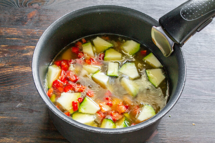 Pouring in broth to simmer the vegetables Vegetable broth being poured into the pot over the chopped vegetables.