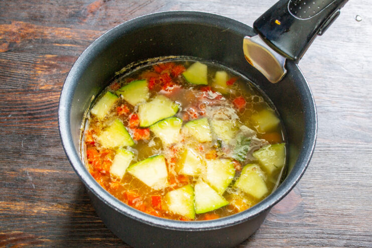 Simmering the soup to soften the vegetables The vegetable soup simmering gently in a pot on the stove.