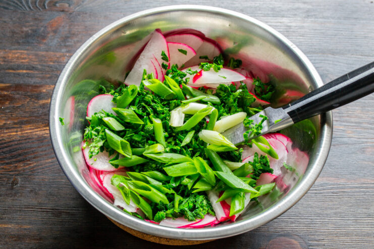 Adding Freshness with Diagonally Sliced Green Onions Green onion stalks being sliced diagonally on a cutting board.