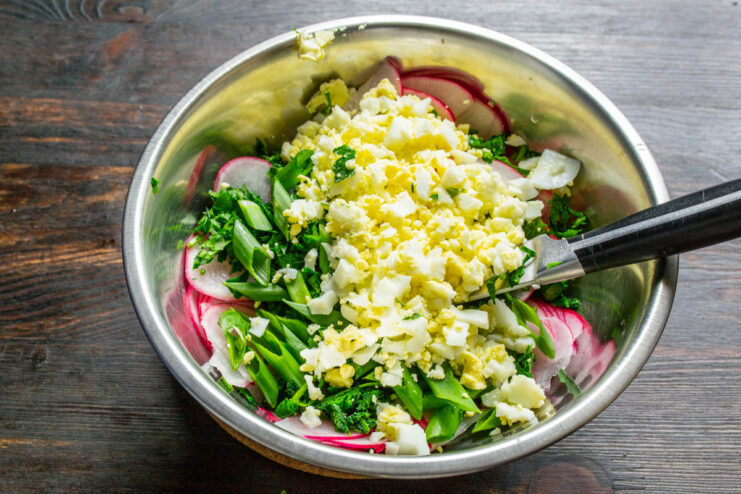 Chopping Hard-Boiled Eggs for a Creamy Salad Texture Finely chopped hard-boiled eggs in a bowl, ready to be added to the salad.