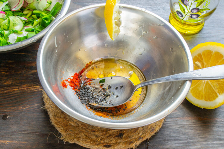 Making a simple lemon and olive oil vinaigrette Lemon juice and olive oil being mixed in a small bowl to create the salad dressing.