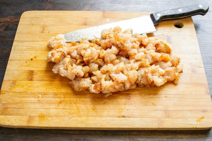 Step 5: Mincing the Chicken Mixture with a Cleaver A meat cleaver chopping the chicken and seasoning mixture on a cutting board.