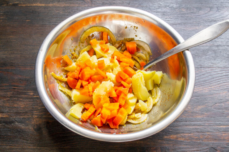 Adding Carrots to the Vinegret Mix Diced cooked carrots being added to the bowl with other vinegret ingredients.