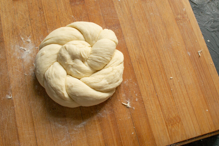Step 10: Forming the twisted dough into a ring shape. The twisted dough rope being coiled into a circular bun shape.