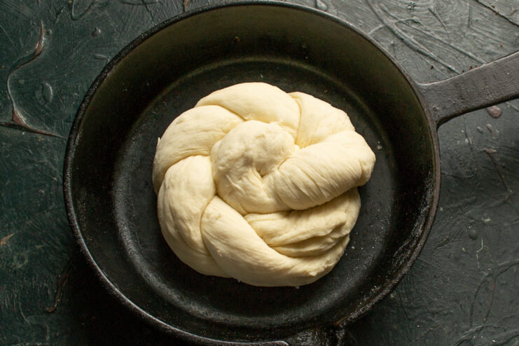 Step 11: Placing the shaped buns for the final proof. A shaped, unbaked Vitushka bun placed in a cast-iron skillet, ready for proofing.