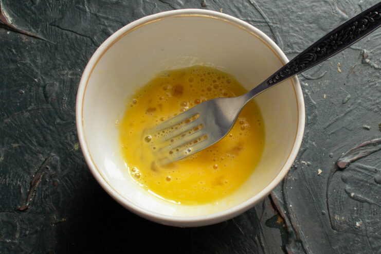 Step 13: Preparing the egg wash for a golden crust. A small bowl with a raw egg being beaten with a fork to make an egg wash.