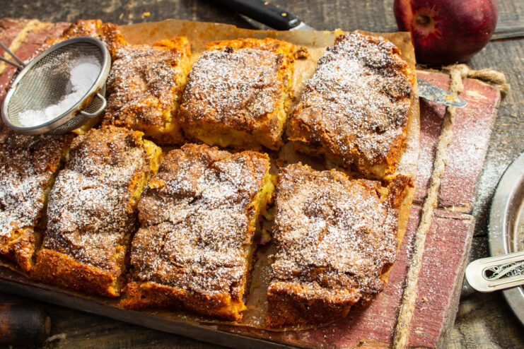 A slice of apple pie with champagne on a plate, dusted with powdered sugar.