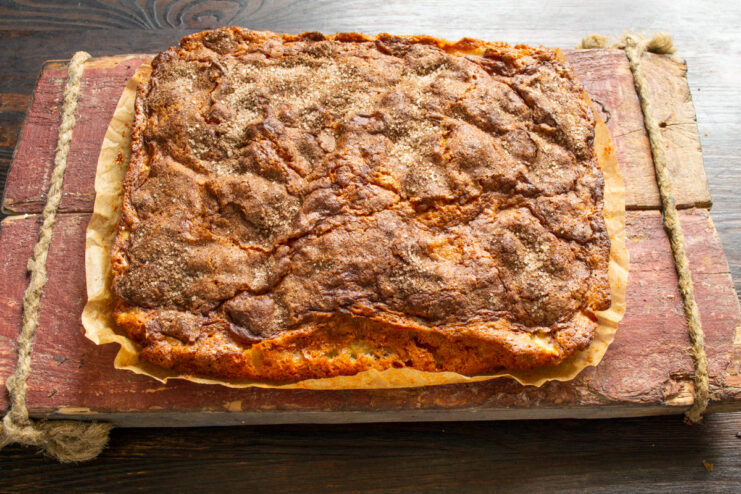 Removing the freshly baked apple pie from the pan The baked apple pie being lifted out of the baking pan using the parchment paper.