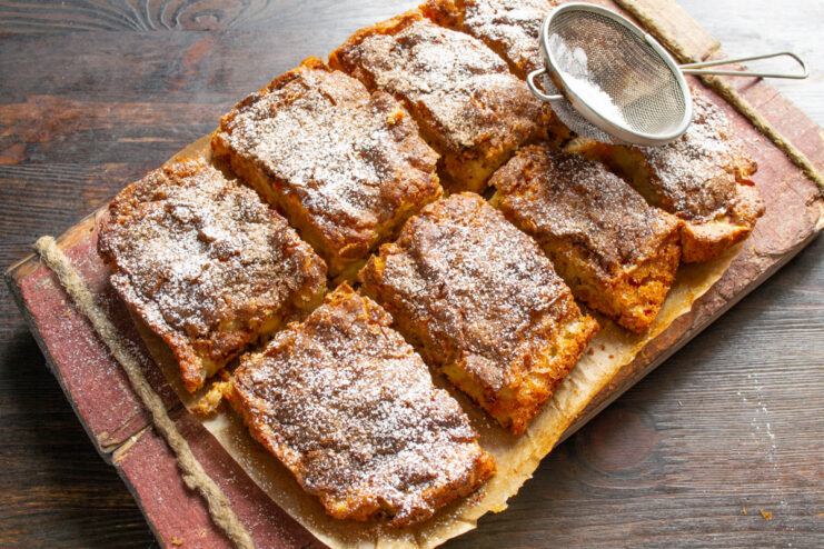 Serving the delicious apple pie with a dusting of powdered sugar A finished apple pie with champagne, cut into squares and dusted with powdered sugar.