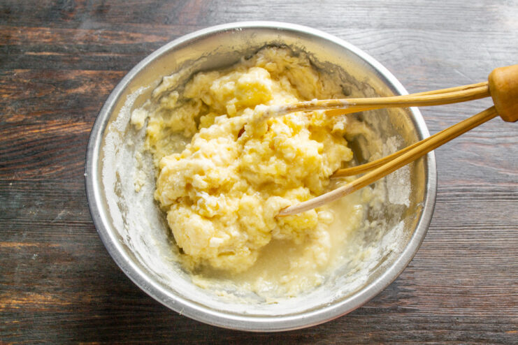 Adding champagne to the batter for a light and airy texture Champagne being poured into the cake batter in a mixing bowl.