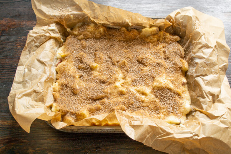 Baking the apple pie with champagne in the oven The apple pie in its baking pan going into a preheated oven.
