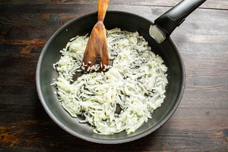 Sautéing Diced Onions for the Egg Pâté Diced onions being added to a hot frying pan with a pinch of salt.
