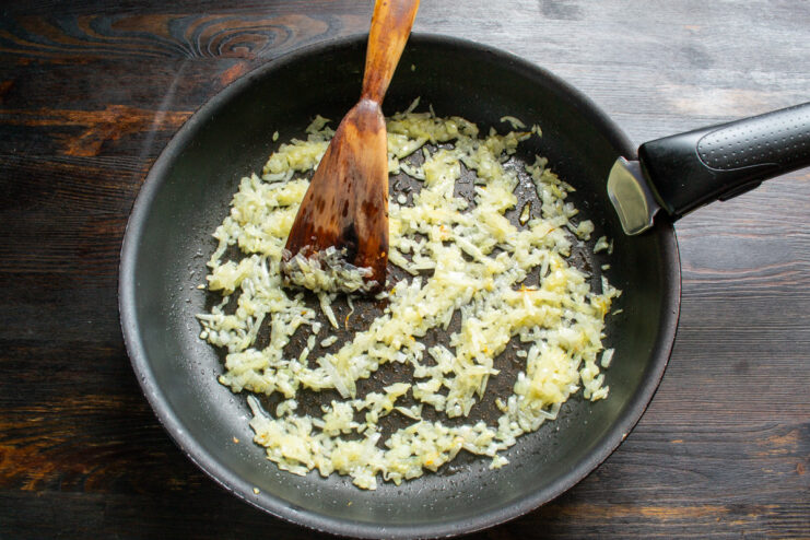 Cooking Onions Until Soft and Golden Onions being sautéed in a pan until they are soft and translucent.