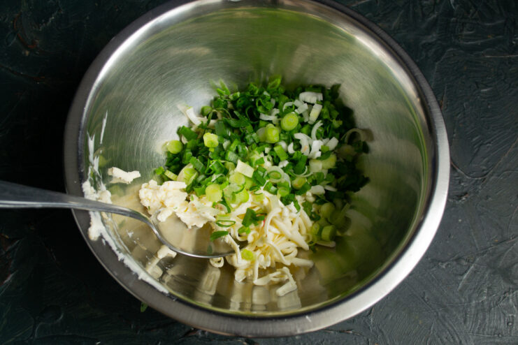 Freshly chopped green onions add a sharp, fresh flavor to the appetizer. A bunch of finely chopped green onions on a cutting board.