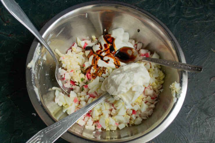 A touch of soy sauce adds a deep umami flavor to the appetizer. Soy sauce being poured into the bowl with the crab stick mixture.