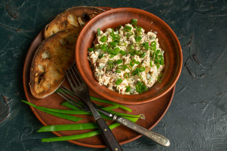Serve the crab stick spread on freshly toasted bread for a perfect appetizer. A bowl of crab stick appetizer served with slices of toasted bread on the side.