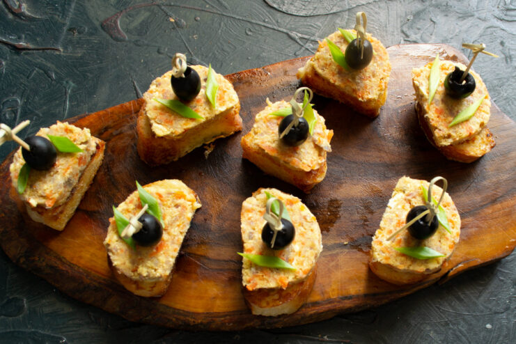 Assembling the herring canapés with pâté and olives Assembling the appetizer: placing a slice of pâté on toast and securing an olive on top.