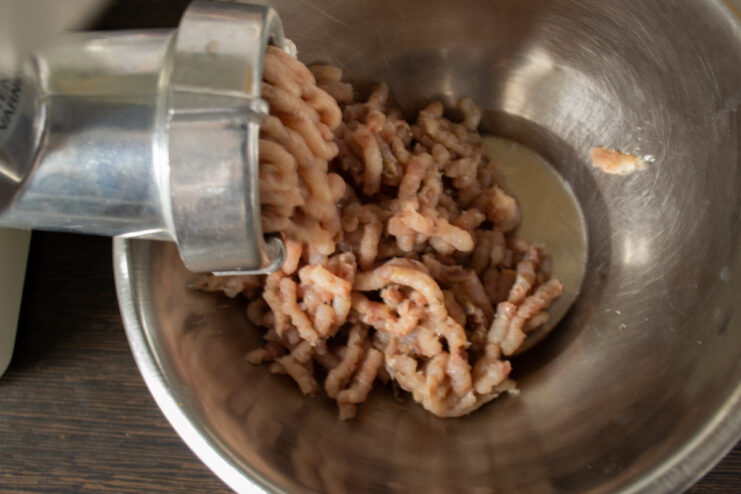 Using a meat grinder to make herring pâté A deboned herring fillet being passed through a meat grinder with a fine plate.