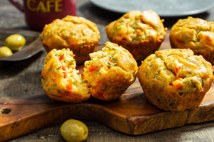 A plate of freshly baked savory muffins with olives and rice flour, garnished with herbs.