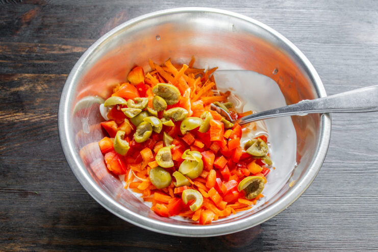 Incorporating Finely Chopped Olives for a Salty Kick Chopped green olives being added to the vegetable mixture in a bowl.