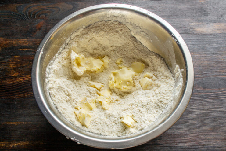 Adding Cold Butter to the Flour Mixture Cubed cold butter being added to a bowl of flour mixture to make shortcrust pastry.