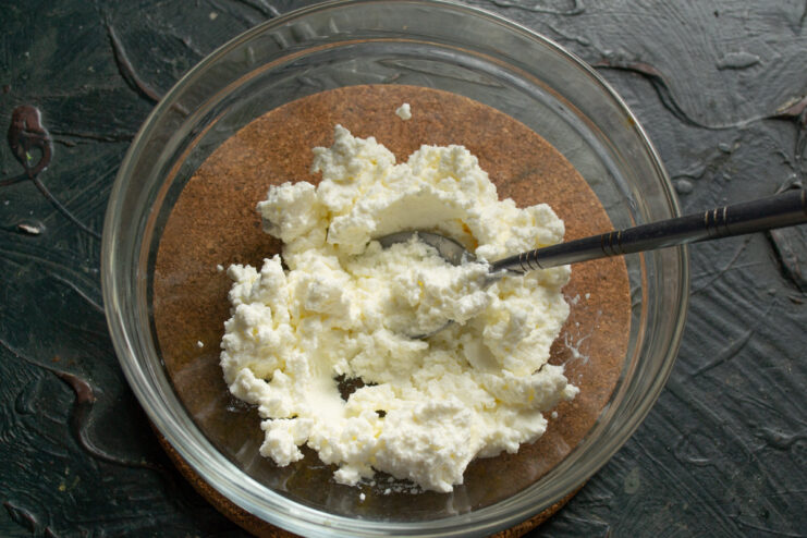 Step 1: Start with a base of creamy curd cheese for the salad. A white bowl with a scoop of creamy curd cheese, the first step in making the salad.