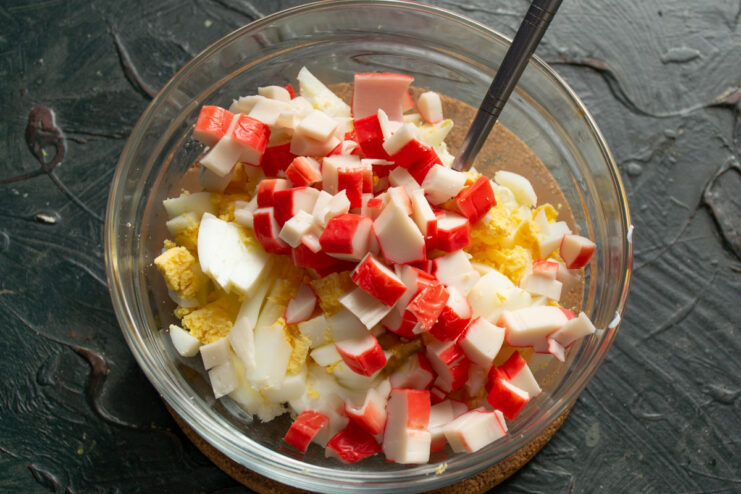 Step 4: Adding diced crab sticks for the main flavor. Diced crab sticks being added to the other ingredients in the mixing bowl.
