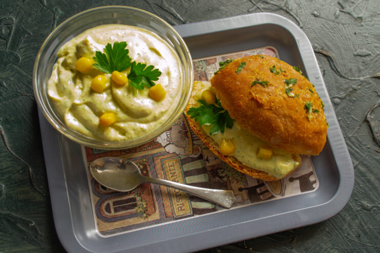 Serving suggestion: Enjoy the creamy crab stick salad on a warm bun. A generous scoop of creamy crab stick salad being placed on a sliced whole-grain bun.