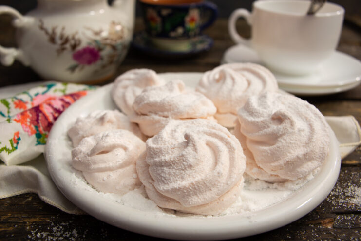 A plate of homemade apple and plum zefir, dusted with powdered sugar.
