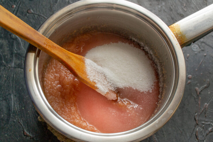 Adding Sugar to the Fruit Puree for Zefir Adding sugar to the thick apple-plum puree in a saucepan.