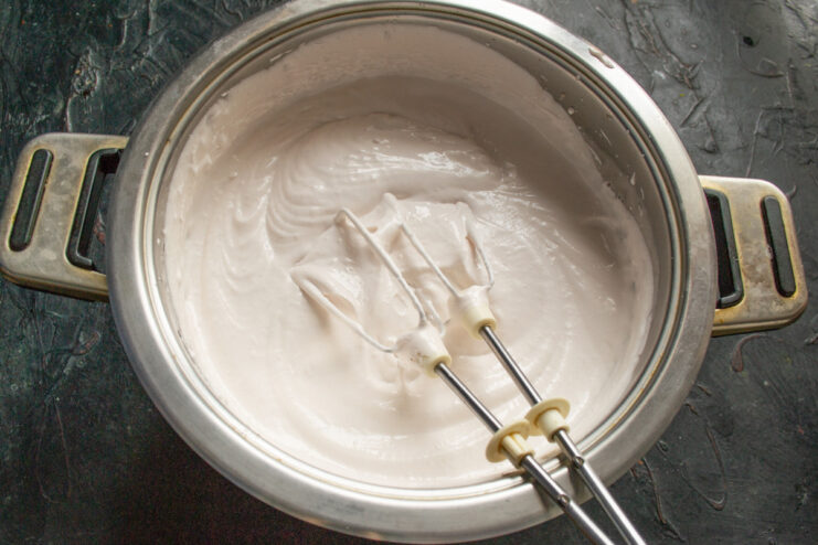 Combining the Hot Syrup with the Whipped Fruit Puree Pouring hot agar syrup into the whipped fruit puree mixture while the mixer is running.