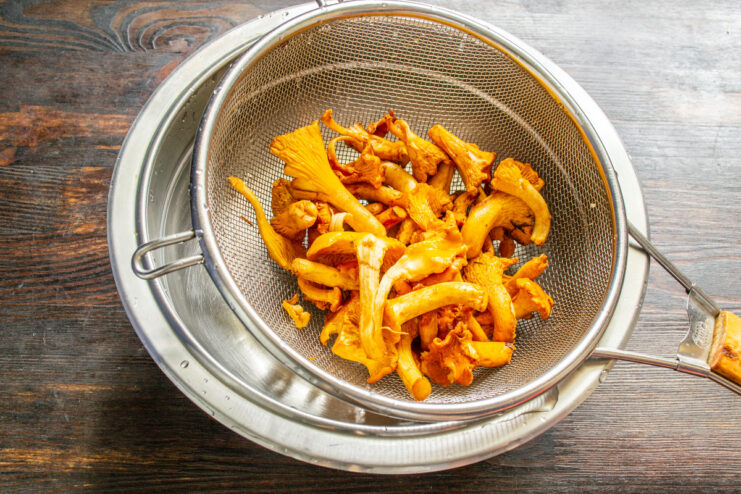 Properly Preparing Chanterelles for Cooking Freshly blanched chanterelle mushrooms being drained in a metal colander.