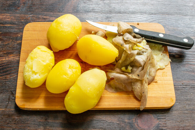 How to Easily Peel Boiled Potatoes A hand scoring the skin of a boiled potato to make it easy to peel.