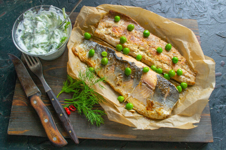 Final Dish: Pan-Fried Salmon with a Refreshing Yogurt Sauce A piece of pan-fried salmon on parchment paper, served with a side of yogurt-cucumber sauce and fresh greens.