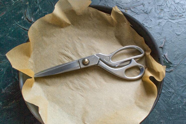 The Secret Trick: Preparing Parchment Paper for a Clean Pan A hand placing a custom-cut sheet of parchment paper into a black skillet.