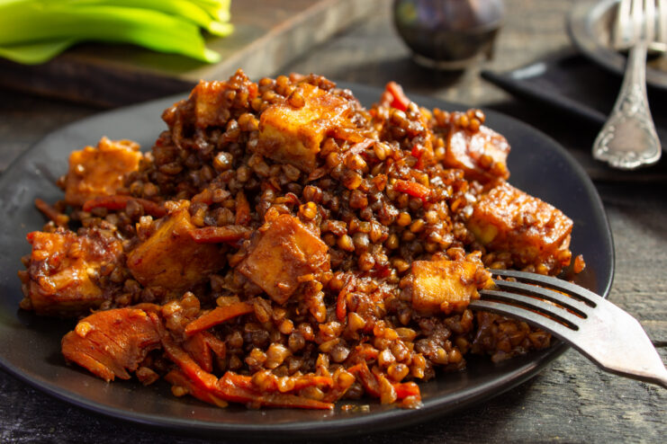A plate of fried tofu with vegetables and buckwheat, ready to serve.