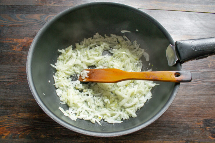 Sautéing Chopped Onion and Garlic in Hot Oil Chopped onion and garlic being sautéed in a hot pan with oil.