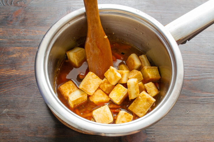 Simmering the Dish on Low Heat for 25 Minutes The pan is covered with a lid, simmering the tofu and buckwheat dish on low heat.